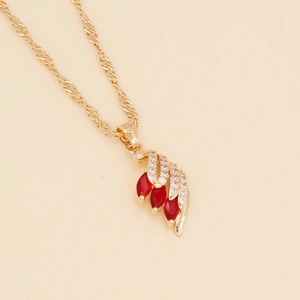Detailed view of a gold feather pendant necklace set with vibrant red marquise stones