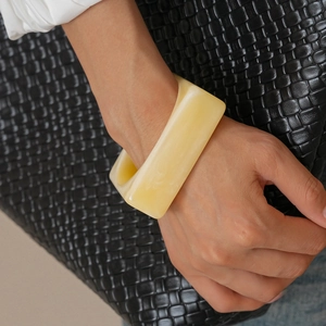 Macro shot of a cream yellow acrylic bangle with marble texture on a model's wrist