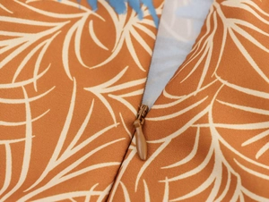 Close-up of invisible zipper detail on brown coconut tree print strapless dress fabric