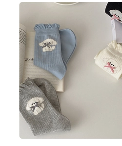Close-up of knit socks with ruffled edges, bow details, and cute puppy embroidery