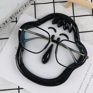 Close-up of black frame glasses with silver metal temples on a cartoon smiley face tray