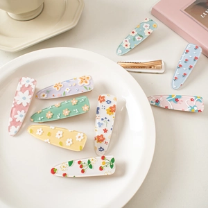 Collection of colorful floral acrylic hair clips displayed on a decorative white ceramic tray