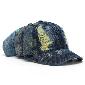 Detail of distressed vintage denim baseball cap with frayed edges and tassel design