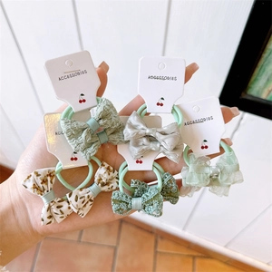 Detail of five assorted floral and lace bow hair ties displayed on cardboard backing