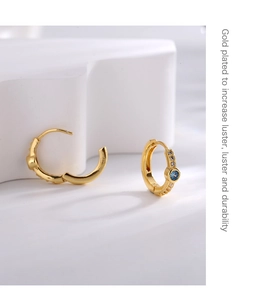 Macro detail of gold plated geometric earrings with blue center stones and zircons