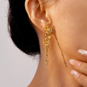 Detail of floral tassel earrings in gold with sparkling rhinestones worn by a model