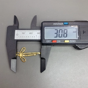 Digital caliper measuring the 30.8 mm length of a gold cubic zirconia bow pendant