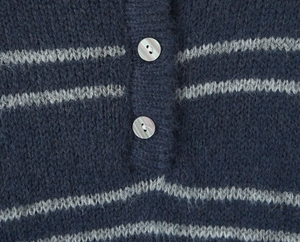 Macro detail of knit polo shirt showing navy stripes and iridescent shell buttons