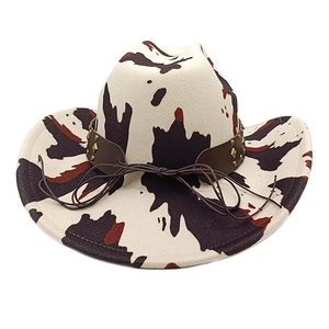 Detail of cow print western hat featuring a brown leather band with gold conical studs