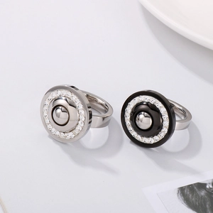Detail of stainless steel rings with zircon inlay and black enamel finish on a minimal surface