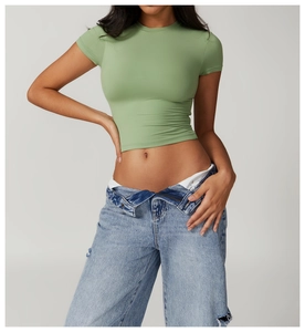 Close-up of sage green slim-fit sports t-shirt showing elastic fabric and cropped waist