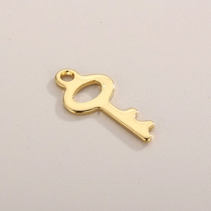 Detailed close-up of a polished gold stainless steel key charm with an open top hole for DIY jewelry