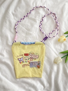 Détail du mini sac jaune en tissu oxford brodé avec une bandoulière tissée colorée