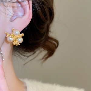 Close-up of French vintage gold irregular branch earrings with elegant white pearls on model