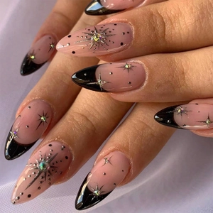 Detail of nude pink almond press-on nails with black French tips and star patterns