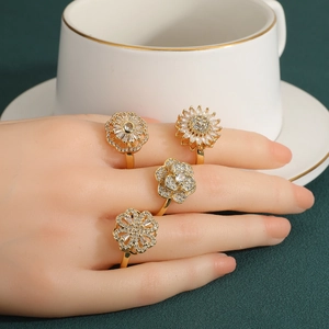 Elegant gold flower rotating rings with clear gems on a model hand with tea cup