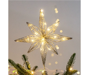 Close-up of glowing silver wire star tree topper with warm LED lights on a Christmas tree