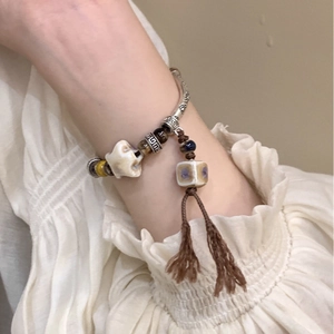 Detailed view of an ethnic pearl and obsidian bracelet with tassels on a model's wrist