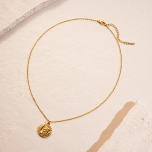 Detailed macro view of 18K gold plated sun coin pendant on a double layered necklace
