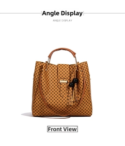 Front view of large brown polka dot tote bag with tassel charm and long shoulder strap