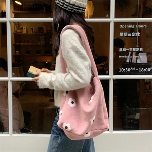 Lifestyle view of a pink plush tote bag with white floral embroidery for autumn winter