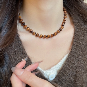 Close-up of tiger eye beaded necklace on a model with vintage brown knit sweater