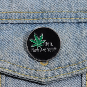 Macro detail of enamel pin with green leaf and text on denim jacket pocket