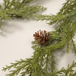 Artificial Christmas cedar garland with realistic green pine needles and a brown pine cone
