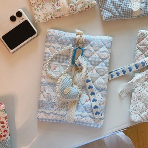 Close-up of blue floral quilted fabric pouch with pearl strap and heart charm detail