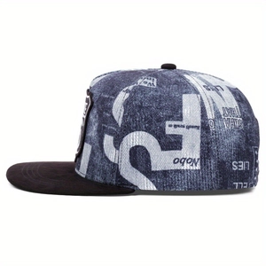 Dettaglio del cappello snapback in denim blu con scritte bianche e toppa nera ricamata