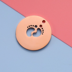 Detail of rose gold round pendant featuring a hollow baby footprint design on split background