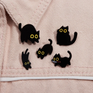 Five cute black cat enamel pins in different poses pinned on pink denim fabric