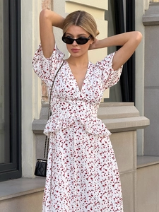 Détail d'une robe mi-longue fleurie à col en V, manches bouffantes et taille peplum