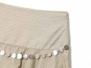 Détail d'une jupe midi rayée kaki avec ceinture décorative à disques métalliques argentés