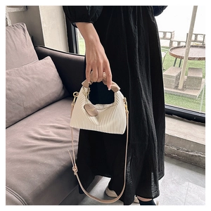 Detail of cream pleated leather bag with brown handles and golden hardware accents