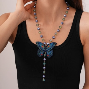 Long necklace with large blue embroidered butterfly pendant and purple pearls on a model