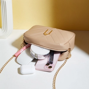 Beige quilted chain crossbody bag with V-shaped stitching and gold hardware detail
