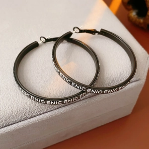 Vue macro de créoles en cuir noir avec motif de lettres blanches sur boîte en velours