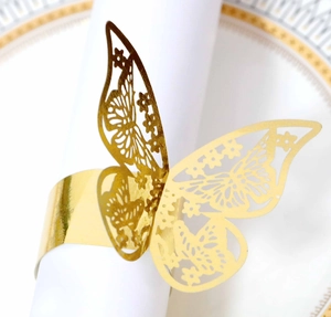 Close-up of golden butterfly napkin ring with laser-cut details on white napkin