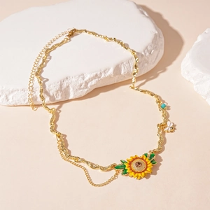 Detailed close-up of a gold sunflower and bee pendant necklace with enamel finishes