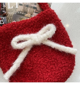 Detailed shot of red faux fur bucket bag featuring a large white knit bow accent
