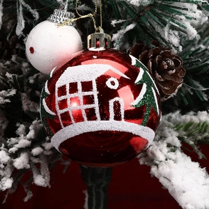 Close-up of red Christmas ball with white glitter snowy house pattern and gold cap