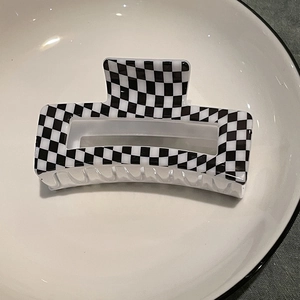 Macro view of checkered black and white rectangular hair claw clip on ceramic dish