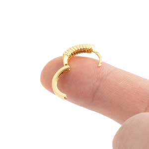 Goldener Creolen-Ohrring mit Zirkonia-Inlay am Finger zur Größenmessung gezeigt