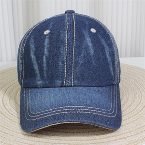Détail d'une casquette en denim délavé avec surpiqûres jaunes et œillets brodés blancs