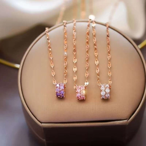 Detail of three rose gold necklaces with purple, pink, and white crystal cylinder pendants