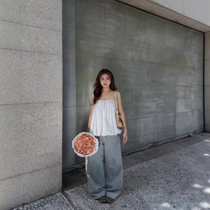 White spaghetti strap bubble top with loose grey jeans on model in outdoor setting