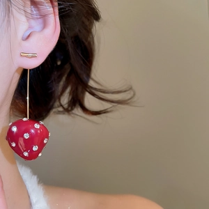 Detailed close-up of a long strawberry earring with crystals and gold needle worn by a model