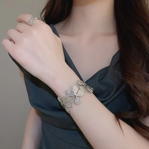 Dettaglio del bracciale rigido a fiore argento vintage e anello aperto in metallo lucido
