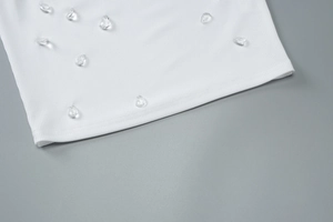 Detailed macro view of white ribbed fabric featuring premium crystal bead embellishments